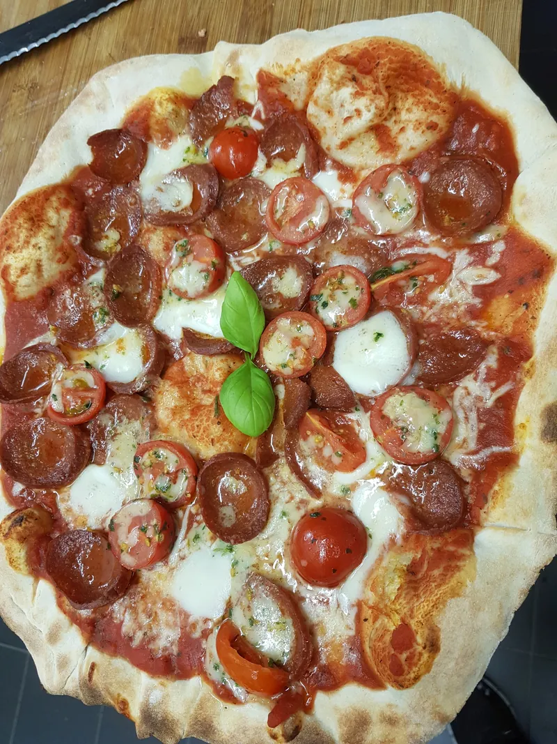 Pizza mit Salami, Kirschtomaten und Basilikum